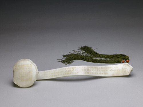 清·乾隆御题青玉和珅隶书如意 青玉质，长45.3厘米。如意头边沿略凸起一周窄边，其上阴刻锦纹。如意头中心留白部位及如意柄正面镌刻楷书乾隆三十年（1765）御题《咏白玉如意》，末署乾隆乙酉新正御笔并阳文比德、阴文朗润二印。柄背面镌刻隶书乾隆四十五年（1780）御题《咏和阗白玉如意》，末署“臣和珅敬书”并阴文乾卦、和珅二印。字之笔画均填金。如意柄末端表面随形凸雕方折几何纹。