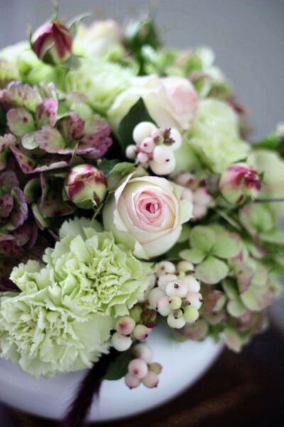  antiqued green hydrangea, pale pink snowberries, spray garden roses (Pierre De Ronsard), sherbet green carnations, and red fountaingrass.