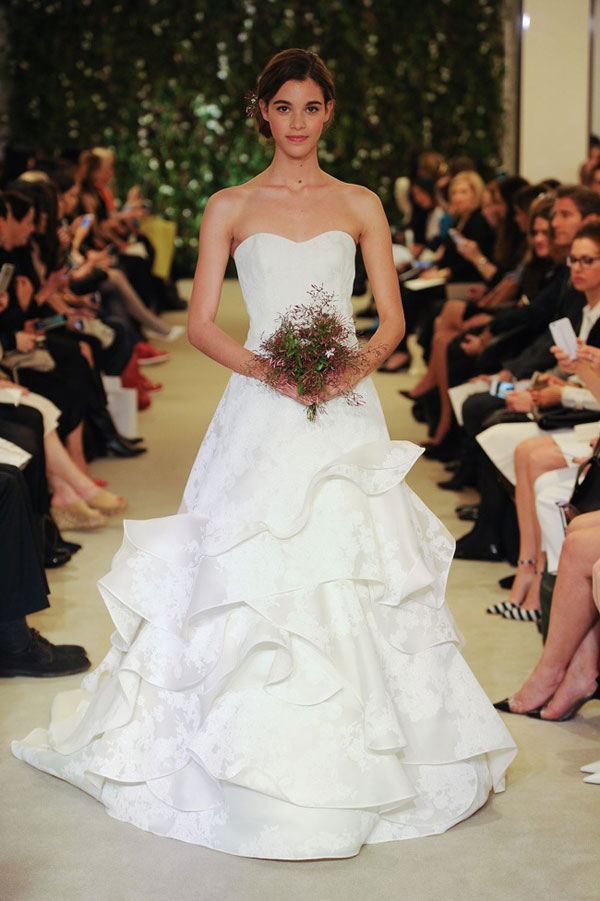  Carolina Herrera Spring 2016 Bridal。卡罗琳娜-海莱娜2016纽约婚纱周春夏系列婚纱礼服秀。本季灵感来源于美丽，性感、芬芳的白色茉莉，以丝绸罗缎上的手工刺绣花卉、层叠错落的蕾丝纱绉，流泻而下的蕾丝羽翼，悄然唤起女人们对于浪漫美学的憧憬与向往。暖色调的灯光照耀下，所有模特穿着婚纱礼服都手捧束花，把大家真正带到了婚礼情境。