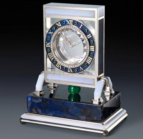 非常精致及罕有，天然水晶，钻石及宝石神秘钟 年 代:约1980 神秘钟由十九世纪的魔术师/ 制表师Jean-Eugène Robert-Houdin (1805-1871) 发明，再由制表师Maurice Couët 专门为卡地亚精心设计，Maurice Couët致力研究16，17以及19世纪初的技艺，团队曾创作数款不同类型的神秘钟，每件都倾尽数月由不下于八个专业工匠包括制表师，设计师，珐琅师，宝石工匠，镶嵌师，雕刻师和抛光师进行华美装饰。 神秘钟利用视觉欺骗的技巧，做出漂浮错觉，奇幻而令人着迷。此款神秘钟名为「Model A」神秘钟，指针悬浮于盘面之上，丝毫没有连接机芯。而事实上，两个指针