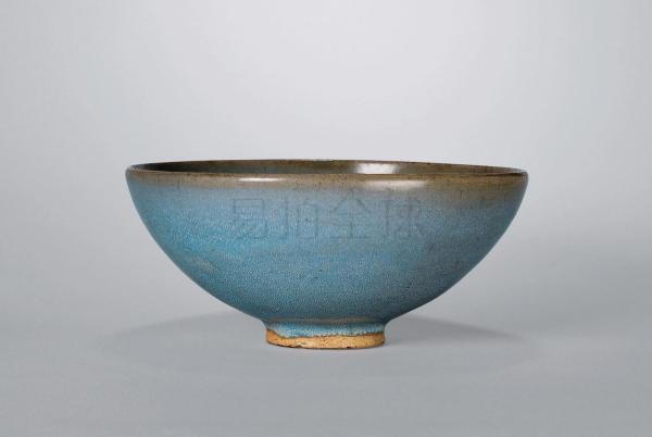 钧窑天蓝釉碗 H 10 cm. D 22.5 cm. 年 代:宋 1. 《中国宋代陶瓷特展》库利尔美术馆，1959年，编号53。 2.
《宋影瓷韵》戴维古董，2004年，页54。 此碗敞口，斜鼓腹，下腹急收聚于圈足。圈足露胎，表面施罩「芝麻酱」化妆釉，局部露出底层胎土，质地厚重。碗内外满施天蓝釉，碗口挂薄釉，呈酱色，而至碗口以下「堆脂」愈厚，其蓝更浓。表面满布鬃眼，更有一层白色结晶。酱色一圈如黄云压顶，而天蓝一片如苍穹无垠，鬃眼结晶如千山急雨，一时难分天地上下，气象万千。