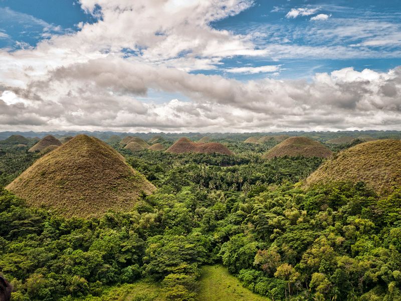 【菲律宾保和岛巧克力山 Chocolate Hills in Bohol, Philippines】巧克力山是菲律宾保和岛中部，卡门附近一处自然奇景。由1268个圆锥形小山丘组成的巧克力山，高度介于 40到120公尺之间。每到夏季，“干草堆”都会干枯，转为褐色，犹如一排排的巧克力排放在大地上，巧克力山这个名字由此而来。巧克力山都由石灰岩组成，可没有一般石灰岩地区所常见的溶洞系统或地下通道。这些山丘像田野上的干草堆一般紧挨在一起。有些有圆顶，其他的呈锥形。它们上面覆盖着乱草，在雨季时色彩呈彩绿。在2—5月份的旱季里，炎热的太阳将这些草晒干，变成巧克力般的褐色。山丘的名字便是这样得来的。巧克力山的