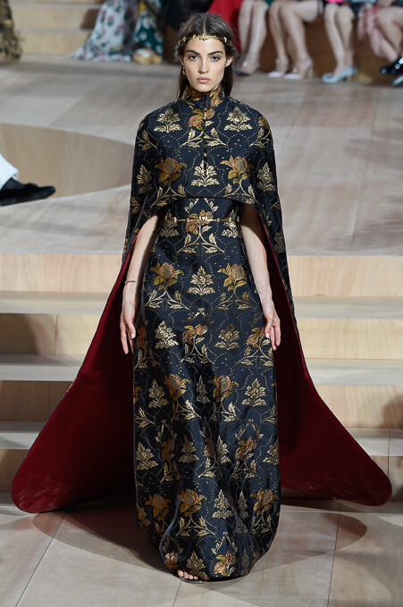 Valentino Fall 2015 Haute Couture。华伦天奴2015秋冬时装周高级定制发布。自1960年品牌创立，Valentino 已经牵手这座古老而神秘城市走过五十余载。本季选址在罗马人民广场，为此次大秀增添了一份怀古颂今的氛围。垂直而修长的线条一直都是Valentino最爱用来刻画庄重华贵造型的手法，教士袍与斗篷的简约设计强有力的刻画出罗马的神韵，又透露出古老世界中罗马战士的身影。瑰丽的锦缎与丝绒搭配华丽的镶边，奢华呼之欲出。象征着罗马权力与繁荣的雄鹰图案出现于礼服之上，为肃穆与庄严增添了一丝傲然于世的尊贵。