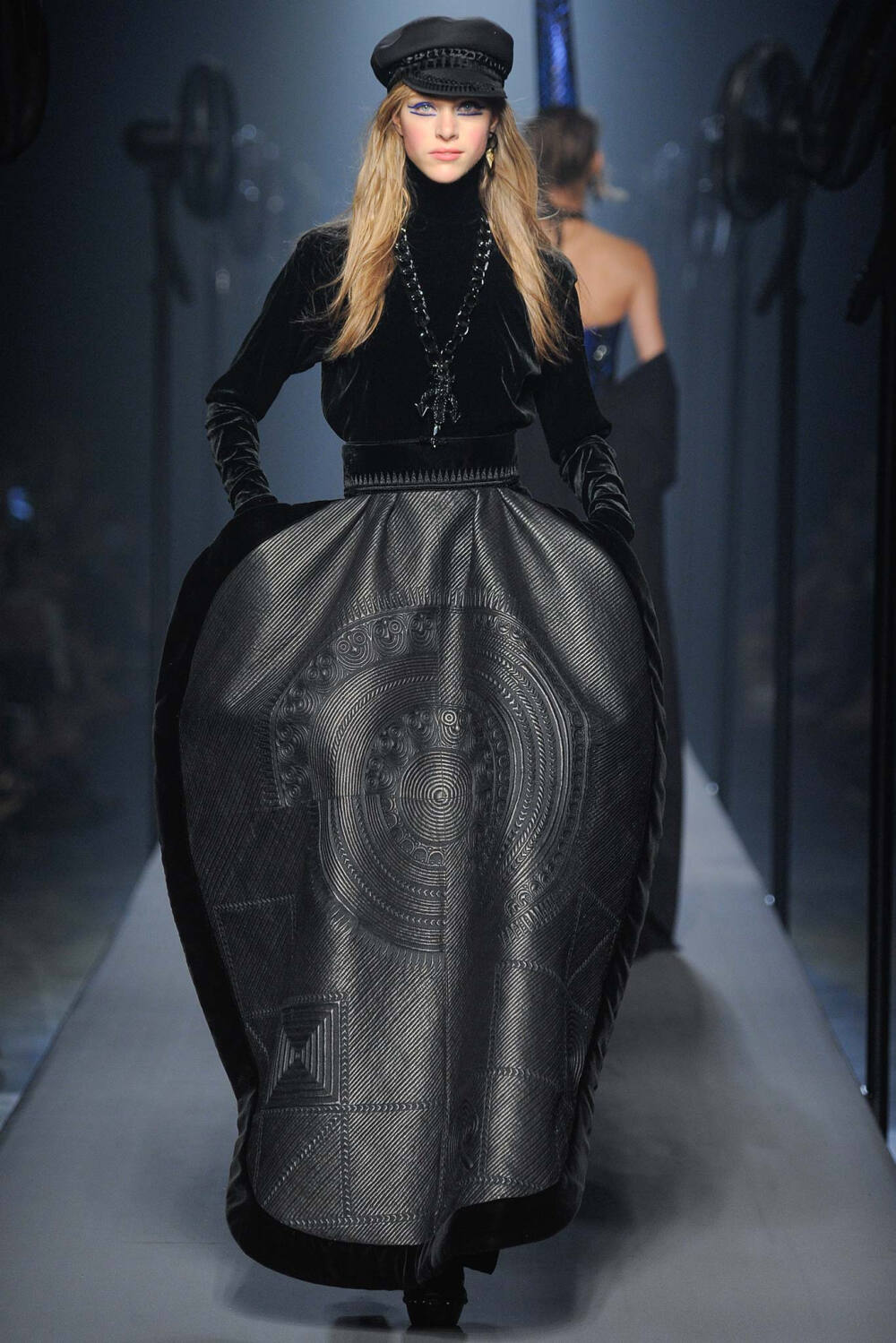 Jean Paul Gaultier Fall 2015 Couture。让·保罗·高缇耶2015秋冬高级定制时装周。本季灵感源于法国布列塔尼 (Brittany) 地区，这里绚烂多姿的民族服饰为高缇耶开启了一场航海旅程。“条纹”则是贯穿始终。开场的海军条纹直入主题，迸发出畅快呼吸的精神气，而这又不仅仅是一场旅行，更似一局盛大的聚会，狂欢的Party。黑色的主调也不觉单一，多色的火焰式花纹刺绣雕琢着民俗图腾，在裙摆、头饰上绘出历史的传说，极尽奢华，不可小觑的力量从海浪中款款而来。