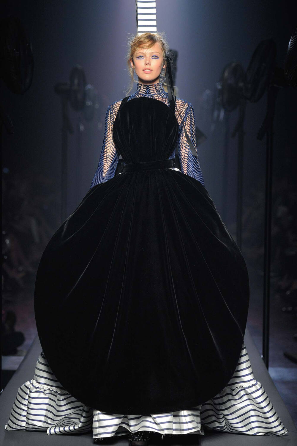 Jean Paul Gaultier Fall 2015 Couture。让·保罗·高缇耶2015秋冬高级定制时装周。本季灵感源于法国布列塔尼 (Brittany) 地区，这里绚烂多姿的民族服饰为高缇耶开启了一场航海旅程。“条纹”则是贯穿始终。开场的海军条纹直入主题，迸发出畅快呼吸的精神气，而这又不仅仅是一场旅行，更似一局盛大的聚会，狂欢的Party。黑色的主调也不觉单一，多色的火焰式花纹刺绣雕琢着民俗图腾，在裙摆、头饰上绘出历史的传说，极尽奢华，不可小觑的力量从海浪中款款而来。