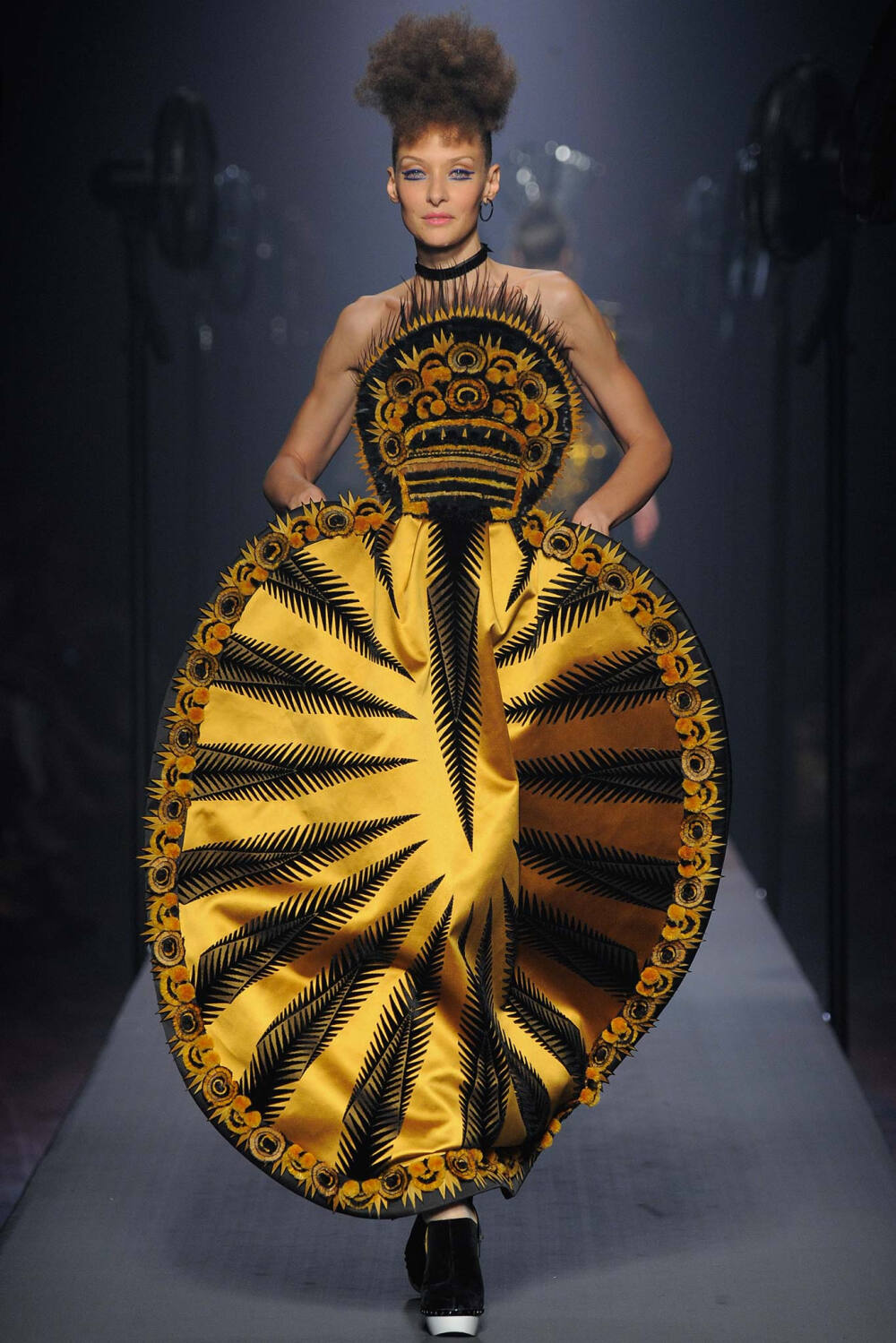 Jean Paul Gaultier Fall 2015 Couture。让·保罗·高缇耶2015秋冬高级定制时装周。本季灵感源于法国布列塔尼 (Brittany) 地区，这里绚烂多姿的民族服饰为高缇耶开启了一场航海旅程。“条纹”则是贯穿始终。开场的海军条纹直入主题，迸发出畅快呼吸的精神气，而这又不仅仅是一场旅行，更似一局盛大的聚会，狂欢的Party。黑色的主调也不觉单一，多色的火焰式花纹刺绣雕琢着民俗图腾，在裙摆、头饰上绘出历史的传说，极尽奢华，不可小觑的力量从海浪中款款而来。