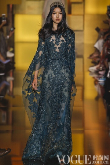 elie Saab 2015秋冬高级定E制发布秀 这次Saab的系列与以往不同的是减轻了装饰的分量，而意境也更为纯真，而少了妖娆。最新鲜的礼服中有一件搭配低跟天鹅绒凉鞋，下摆漫不经心地高于脚踝几吋。另一个给人惊喜的轮廓是直筒衫搭配窄腿长裤和无袖外套，其肩部装饰着环形的皮草。