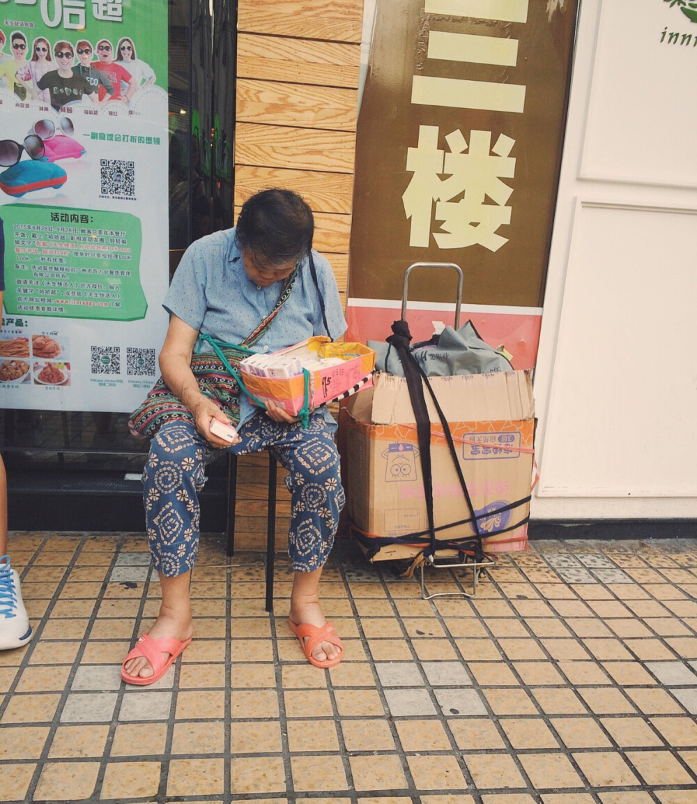 阿婆在街头卖纸巾。困得坐着都睡觉了，生活不易