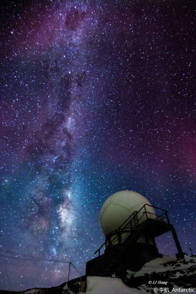 卫星云图接收机上空，大范围的红紫色极光浸染夜空，一旁的银河如巨龙般直贯云霄。