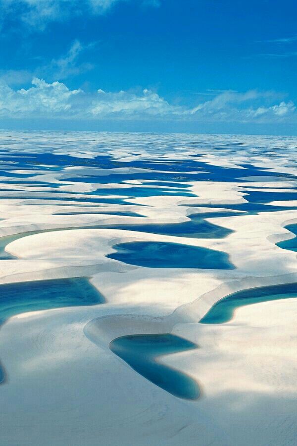 This Lençóis Maranhenses National Park, Brazil。巴西伦索伊斯国家公园。巴西伦索伊斯·马拉赫塞斯国家公园，位于巴西北部海岸。公园内的白色沙丘（有的有些时候能高达40米高）之间点缀着水晶般蔚蓝的礁湖，在一片完全像沙漠的景象中形成了一个个的热带园地。湖水有三米深，维持在三十摄氏度，一年中的很多时候都可以在这游泳。该公园看起来像是一个巨大的自然水上公园。