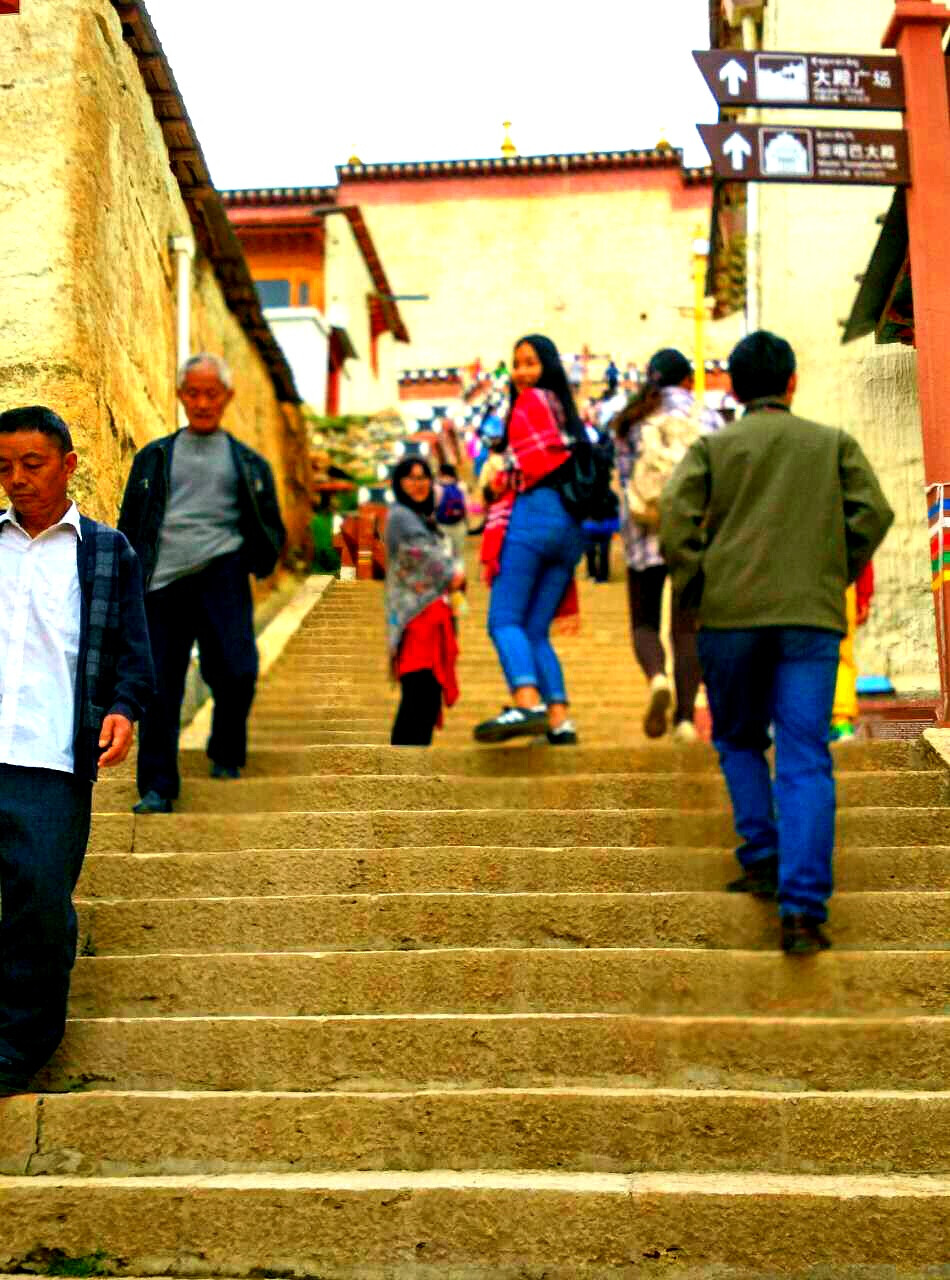 云南，香格里拉，松赞林寺（小布达拉宫） 非常的喜欢这张照片，虽然是因为摄影师不小心调错了焦距而拍摄下来的。去寺庙的路上，一阶一阶的楼台上，你穿过人群，逆流之中，仄头回眸，然而所有人都可以是清晰的，只有你，照片正中的，回头者。 我说，这张照片叫，穿过人海，最后模糊的却是自己。 ——摄影（萝卜）