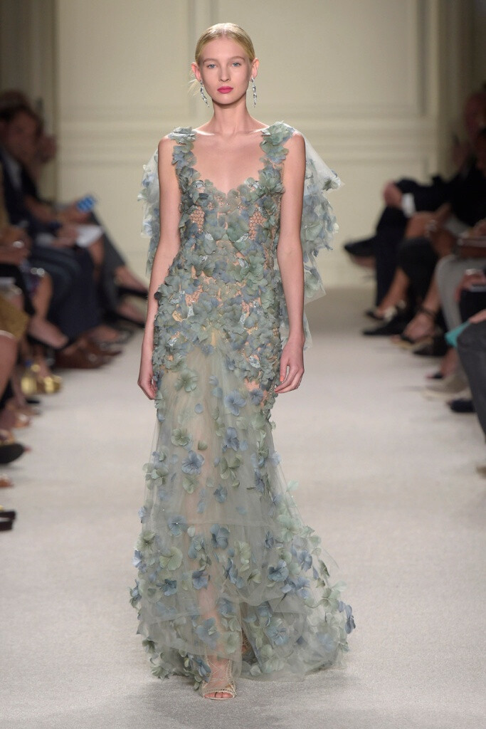 Marchesa Spring 2016 Ready to Wear 。玛切萨2016纽约时装周高级成衣系列。本季运用花朵的元素，黑色的镂空轻纱配紧绷的丝带诠释一种阴郁却又唯美的氛围。大片花朵的装饰更是代表了女性浪漫轻柔的气质，层层包裹身体的轻纱飘逸又服帖，场面好似不同风情的花仙子在从中嬉戏。