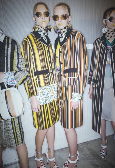 Prada S/S 2016 Milan - Backstage. 金色唇妆与Disco灯球耳饰，条纹拼接着威尔士亲王格纹，复古着时髦的Prada女郎。