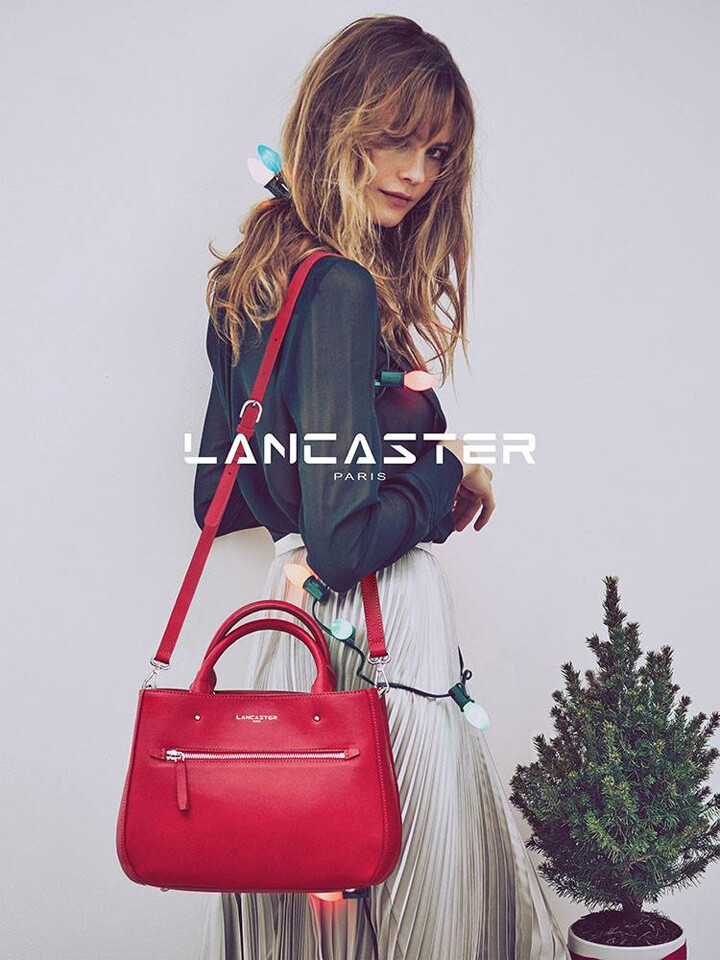 法国知名皮具品牌 Lancaster（兰嘉丝汀）释出最新2015圣诞系列广告大片，维密天使超模 Behati Prinsloo（贝哈蒂·普林斯露）再度出镜代言，摄影师 Guy Aroch 执镜。贝哈蒂拿着扎着红色蝴蝶结的小盆圣诞树游走于城市各处