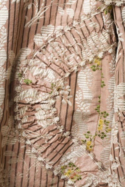 Detail decoration, robe à la francaise (sack-back gown), France, 1760-1780. Striped salmon-coloured brocaded silk. A white leaf pattern is woven into the fabric and as well as floral sprays in various…