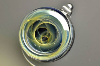 日本的玻璃艺术家Satoshi Tomizu制作了一系列斑斓美丽的玻璃球，并在里面雕画了整个太阳系和银河宇宙。行星由猫眼石以及纯金碎片制作而成。彩色玻璃拉出星轨的形状，好似在宇宙中不停运动和旋转。（照片对球体内的细…