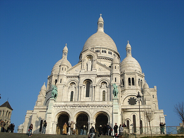 圣心大教堂色彩浑凝，雄伟地耸立在巴黎北部的蒙玛特尔山上，在树丛中看它，真像童话世界里的天堂一样圣洁美丽。该教堂是巴黎建成最晚的大教堂，其风格奇 特，既像罗马式，又像拜占庭式，它的四圆屋顶和一个大圆屋顶是典型的拜占庭建筑风格。圣心教堂不仅是个著名的教堂，也是个游览胜地。由于地势高，人们喜欢 来这里，站在教堂门口，俯瞰巴黎市的全景。教堂周围是古老狭窄的小街道，法国历史上有名的&amp;quot;蒙玛特尔&amp;quot;高地即指这里，当时有许多作家、艺人曾居住在这里。 至今还保持着传统习惯，许多画家来这里当众作画并公开出售他们的作品。