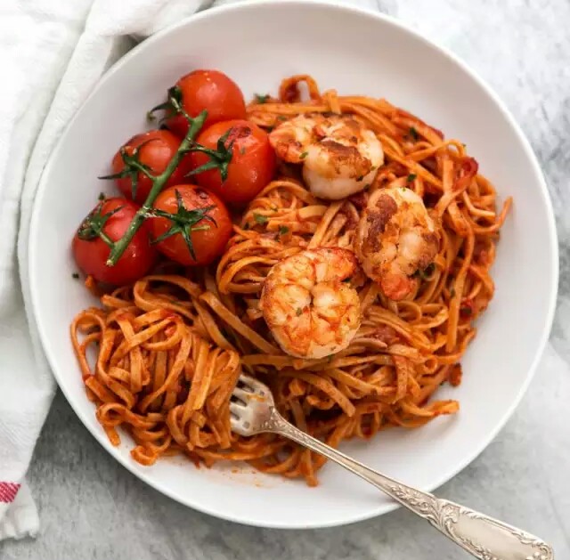 【鲜虾番茄意面】 食材：虾（去壳去内脏），扁意面，3汤匙橄榄油，1个大洋葱（切碎），4-5瓣大蒜（切碎），2汤匙番茄酱，半杯红酒，香菜，半茶匙辣椒粉，樱桃番茄，3汤匙黄油，糖，盐和胡椒。 做法：1、锅加热，加入橄榄油和洋葱翻炒约5分钟，加入大蒜，继续煮一分钟。2、加入虾，再煮3-4分钟。3、加入番茄酱搅拌，再加入红酒煮2-3分钟，加入香叶，辣椒粉，糖，盐和胡椒小火加热15-20分钟。4、同时，根据包装上的说明煮意面，煮好以后沥干。5、平底锅加热，倒入少量橄榄油，加入樱桃番茄，煮2分钟后盛出。6、锅中放油，虾放入锅中煮约3分钟，用盐和胡椒调味。7、再将番茄放入锅中一起翻炒，盛于碗中搅拌意面即可。