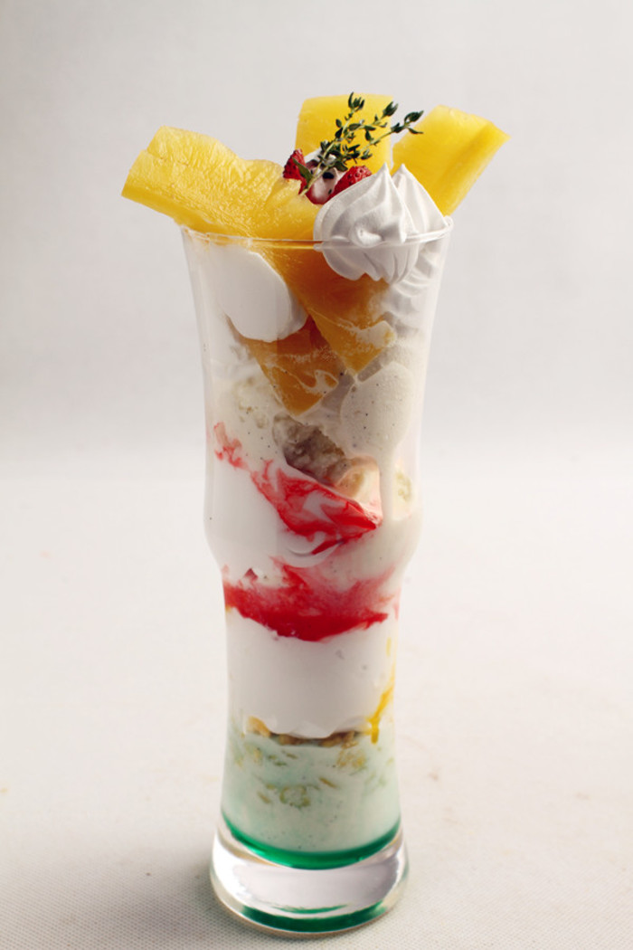 【凤梨百汇】材料： 薄荷糖浆10ml 石榴糖浆10ml 芒果浓缩汁10ml 菠萝片4片 草莓1个 玉米片适量 打发鲜奶油适量30克 香草冰淇淋球6个制作： 1、将薄荷糖浆倒入杯底，放上1个香草冰淇淋球，再撒上玉米片。2、挤上鲜奶油，接着倒上芒果汁，在上面放上2个冰淇淋球，再挤上鲜奶油。3、淋上石榴糖浆，在上面放上3个香草冰淇淋球，再挤上鲜奶油。4、最后放上菠萝片和草莓装饰，挤上鲜奶油即可。