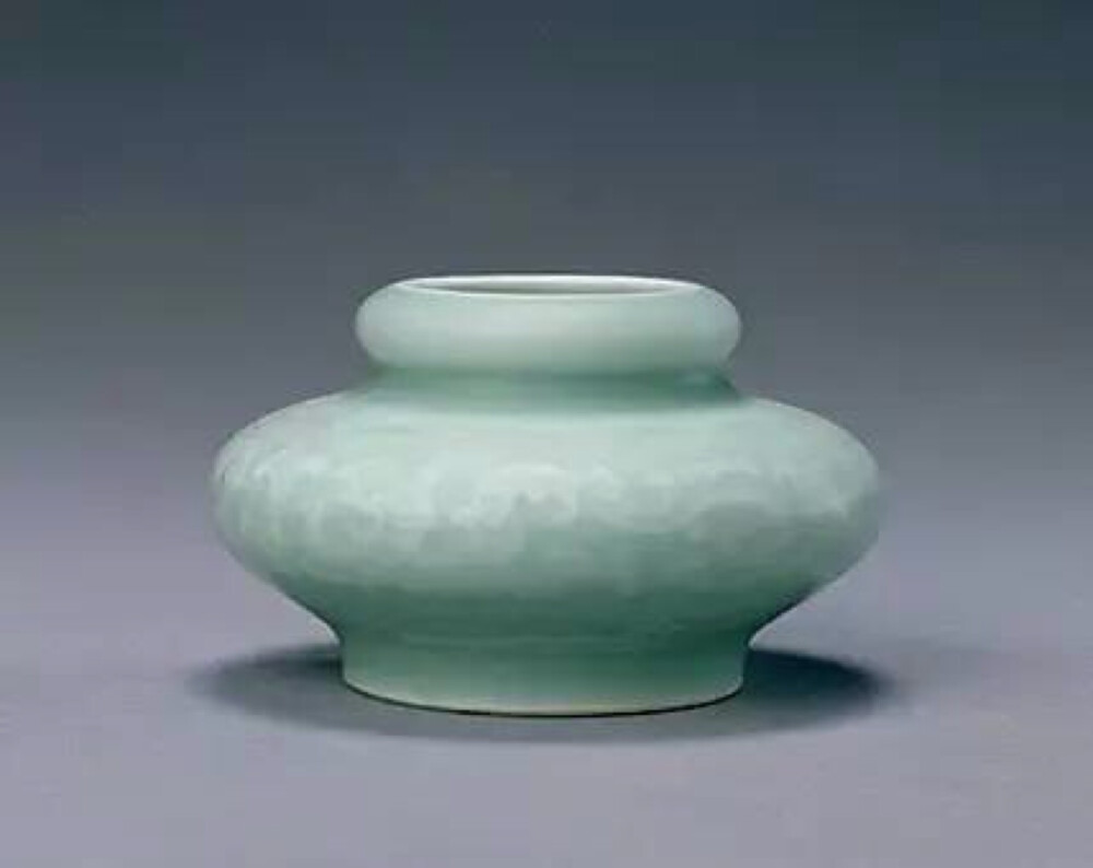 粉青釉暗夔龙纹洗口水丞 清乾隆，高5cm，口径3.3cm，足径5cm。清宫旧藏 水丞洗口，束颈，扁圆腹，腹以下收束，圈足。足内有青花篆书“乾隆年制”四字款。里外施粉青釉，肩部有暗印花如意头纹饰一周，腹部为夔龙纹，近底处为莲瓣纹。釉面匀净，制作精美。