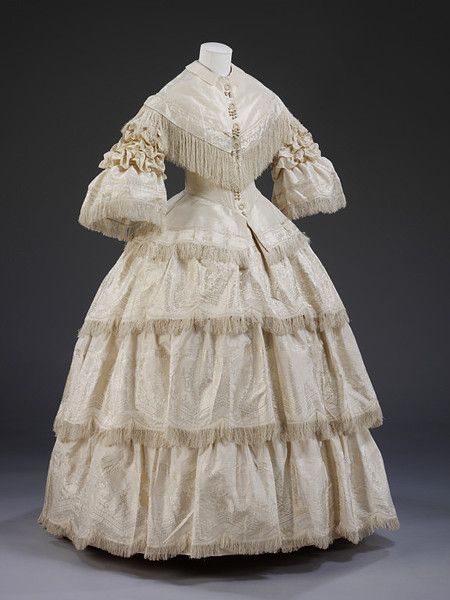 Wedding dress of ivory figured silk with second evening bodice, England, 1857.