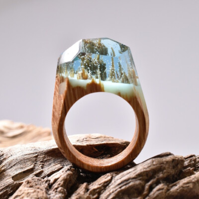 加拿大珠宝商“Secret Wood”出品的戒指，由木材、树脂和蜂蜡制作。木头的断面在树脂中形成了奇妙的微型自然景观。