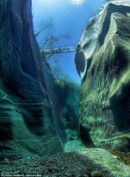 The Verzasca River,Switzerland (by Photographer Claudio Gazzaroli )。瑞士韦尔扎斯河，这条河流经瑞士阿尔卑斯山南部的韦尔扎斯卡山谷。“在几百万年的时间里，韦尔扎斯卡河在岩石中切开一条通道，使岩石面变得平滑而光亮。然而，38岁的摄影师Claudio Gazzaroli大胆搞出了不寻常的名堂。他带着相机，跳入50英尺（约15米）深的河底，仰望天空，拍摄了一般人看不到的水下风光