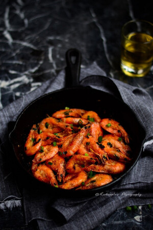 蒜香椒盐虾做法：材料：中等大小的鲜虾300克 淀粉1汤勺 料酒半汤勺 盐少许 小红辣椒2~3个 蒜5瓣 青葱一大把 椒盐粉1勺 1 将虾洗净，不去头，用牙签从虾背第二节处挑出虾线，剪去长须后加料酒拌匀，待10分钟，再用厨房纸擦去多余水分。加淀粉充分拌匀使虾均匀裹满淀粉。蒜剁蒜蓉，红辣椒切细末，青葱切碎 2：锅内入两勺油，加热至6成热时下虾半煎炸。至虾变色时盛出，大约3~4分钟左右。留少许虾油，中火下蒜蓉，葱和辣椒末一起翻炒出.jpg