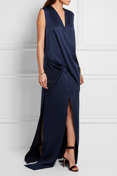 Solace London 的设计以较为宽松的略长廓形打造出摩登气质。这款 “Erica”
礼服选用柔滑的缎布制成，正面采用垂坠感围裹设计，曳地裙身则配有不对称开衩。不妨以酒红色高跟鞋映衬优雅的海军蓝色。