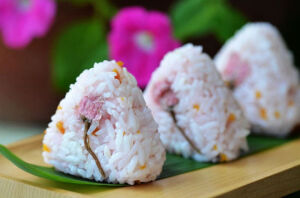 做法步骤
1盐渍樱花清洗一遍，再用清水泡半个小时去除盐味
2五常大米像平时煮饭一样煮熟备用
3紫苏梅子取梅子肉切成细末
4酸甜味儿的泡菜萝卜切丁（用粉色的泡菜萝卜）
5红苋菜洗干净后用开水焯一下取汁少许
6米饭放入大碗中，加入切碎的紫苏梅、泡菜萝卜和苋菜汁，用勺子搅拌均匀
7将拌好的米饭放在三角饭团模具中，上面再放一朵挤去水分的樱花，压出形状，樱花饭团就做好了
烹饪小窍门
如果没有酸甜口味的泡菜萝卜，就加点点寿司醋吧
お花見気分で桜おむすび♪ ＆ ご飯のお供に！生姜ピーマン