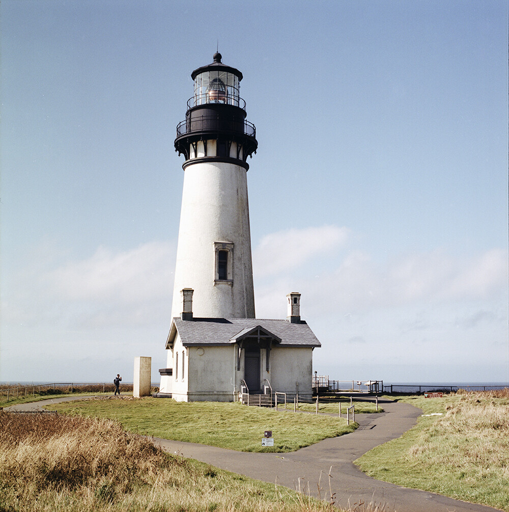 Yaquina Head Lighthouse
太平洋西北海岸那么多景点，Yaquina却有它的独特之处。这里的海滩没有细沙，取而代之的是黑色的鹅卵石。海浪拍打着堆积在岸边的小石头，撞击之间发出叮叮咚咚清脆的响声，非常特别。
Yaquina灯塔所采用的菲涅耳镜头在法国巴黎制造，1873年运抵俄勒冈后首次点亮并使用至今。规模较大的灯塔通常有一个管理员和两个助理，管理员和一级助理的家人均在此居住，二级助理则往往是个单身汉。遥想百年前，交通不发达，灯塔又往往位于距离城镇遥远的海岬处，大一点的Yaquina或有好几人在那里工作，小一点的灯塔有时仅有一两个人驻守。我难以想象经年累月独自面对太平洋的寂寞