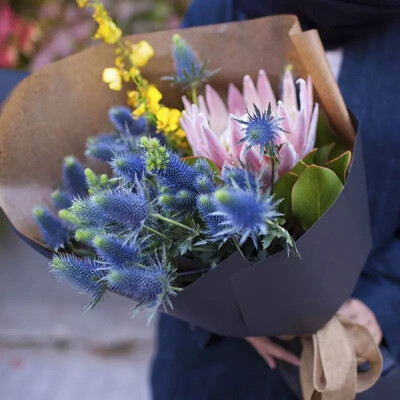 上图的粉红色主花帝王花，搭配蓝刺芹，以及一只明黄色的跳舞花做亮色的衬托。送男友呀朋友呀都还挺衬的，会觉得硬朗，干脆和明快。而且帝王和蓝刺芹都属于可以放成干花的种类，不会凋谢，可以长久保存~