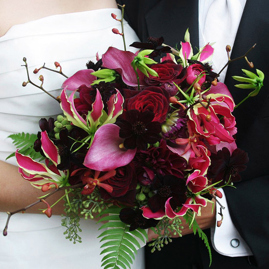 All shades of red -- from magenta to wine -- come together in this round bouquet. Chocolate cosmos, calla lilies, gloriosa lilies, dahlias, orchids, seeded eucalyptus, and ferns are arranged informally for a fresh-from-the-garden look.