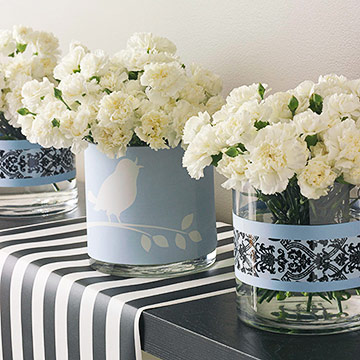 Paper-Banded Containers Embellish glass containers to further the motif of the wedding reception. Fit bands of paper and tape around containers. Fill with simple white carnations.