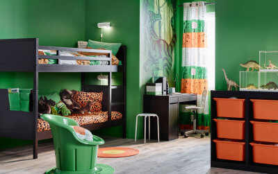 儿童房内有一张黑色双层床，一张书桌以及绿色和橙色的织物。