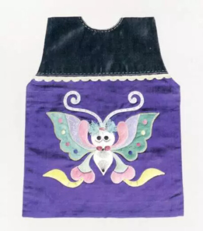 贴绣彩蝶纹兜肚
此肚兜为方形，上半黑地，下半部分紫地上贴绣彩蝶纹，图案精美，做工细致，是清代的传世珍宝。
