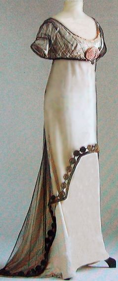 Evening gown called Josephine by Paul Poiret. Ivory satin with a tunic overlay of black tulle. The rose pinned on the bodice became a symbol of Maison Poiret.