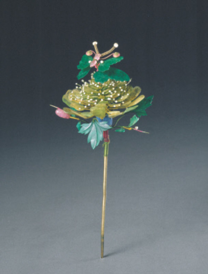 镶宝石碧玺花簪，清乾隆，长25cm，宽12cm。 花簪为铜镀金点翠，上嵌碧玺、珍珠、翡翠。以碧玺做立体芙蓉花，花蕊为细小米珠，花叶为翡翠薄片细雕而成，花蕾为碧玺雕成，花托为点翠。一只蝴蝶停落于芙蓉花上，其翅膀为翡翠薄片雕成，并嵌珍珠、碧玺。整个花簪用料讲究、华贵。