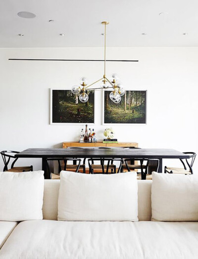 two art prints hung on the wall with modern light fixture hanging over dining table / sfgirlbybay