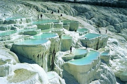 土耳其棉花堡
在土耳其的纺织工业重镇Denizli，位于西南部山区，距离伊兹密尔约二百公里。土文pamukkale是由Pamuk（棉花）和Kale（城堡）两个字组成的，棉花是指其色白如棉，远看像棉花团,其实是坚硬的石灰岩地形。
城堡是说它由整个山坡构成，一层又一层，形状像城堡，故得名棉花堡。
此地多温泉，温泉自洞顶流下，将山坡冲刷成阶梯状，平台处泉水蓄而成塘，人们可坐在里面泡温泉。泉水中的矿物质沉淀下来，把整个山坡染成白色，像露天溶岩。从上往下看，一方方温泉平台像一面面镜子，映照着蓝天白云；从下往上看，像刚爆发完的火山，白色的岩浆覆盖了整个山坡，颇为壮观。棉花堡的形成，正是由于地下温泉水不断从地底涌出，其中含有丰富的矿物质。