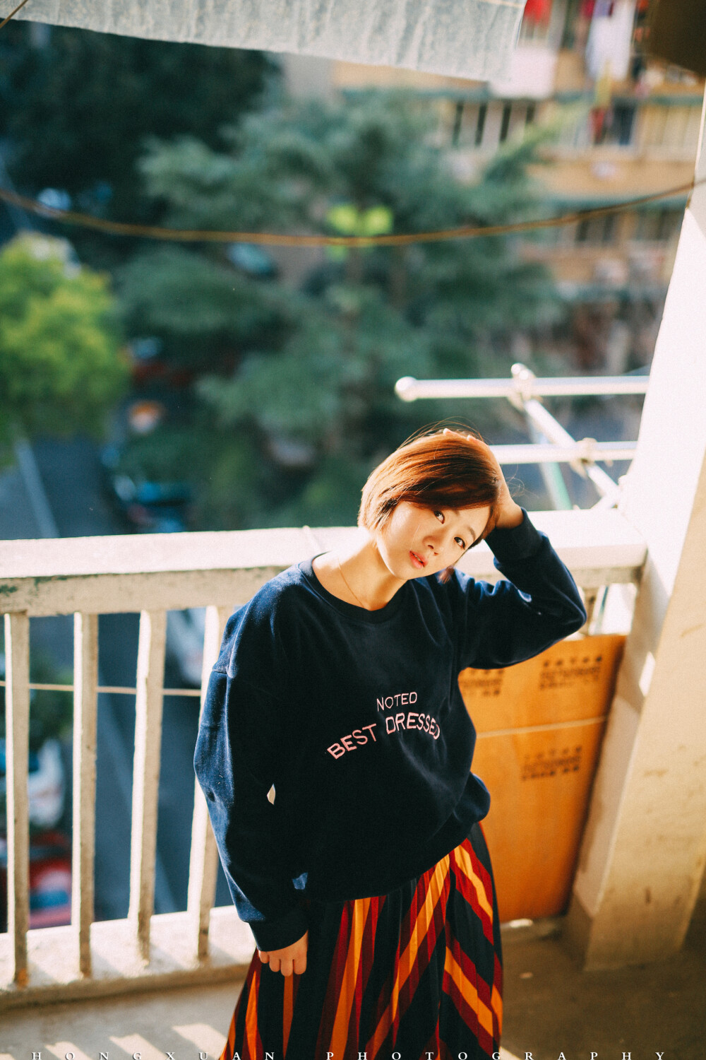 你是我的室友
摄影：洪小漩
出镜：羽希
过年在家，这是一个落寞的春节。我推掉了一些朋友的邀约，在家看日剧，或者陪妈妈寻山访寺，上香祈福。
今年回家发现全面禁烟花爆竹。我看看面目全非却被被赞颂的村庄，心下波澜不惊。这不是我长大的地方，而除夕夜少了鞭炮的轰鸣，也无非是让我更加坚信这一点。
初一那天， 恰好是羽希阳历生日，我给她发了个红包，稍稍聊了几句，新年问候。
年前最后一周的周末，我在社区楼道给她拍的照，因为不知道要写点什么文字，这才修完了却一直没腾出手来发布。
这个姑娘和我做室友也有两年了，我们一起经历了两轮涨房租，一起养了一只叫可乖的猫，一起换了热水器洗衣机，一起粉刷了墙壁。我为护她被一个男人指着鼻子破口大骂，胳膊上让人掐出淤青三周不褪，她为我冲上去直接和人扭打，架势就像一只疯狂的小牛。
我们一起过了一段互相搀扶的日子，那些时日，两个人走路都要左顾右盼，周遭弥漫着不安。
记得有一天，她搂着我泣不成声，哭着说抱歉。不擅长安慰人的我，僵硬地拍着她的后背，说没关系，说我一直在。
后来，从一场糟糕的感情泥沼中得以脱身的好姑娘，遇到了另一个心仪的男生。这个男生在工作日早上为她盛粥煎鸡蛋，周末陪