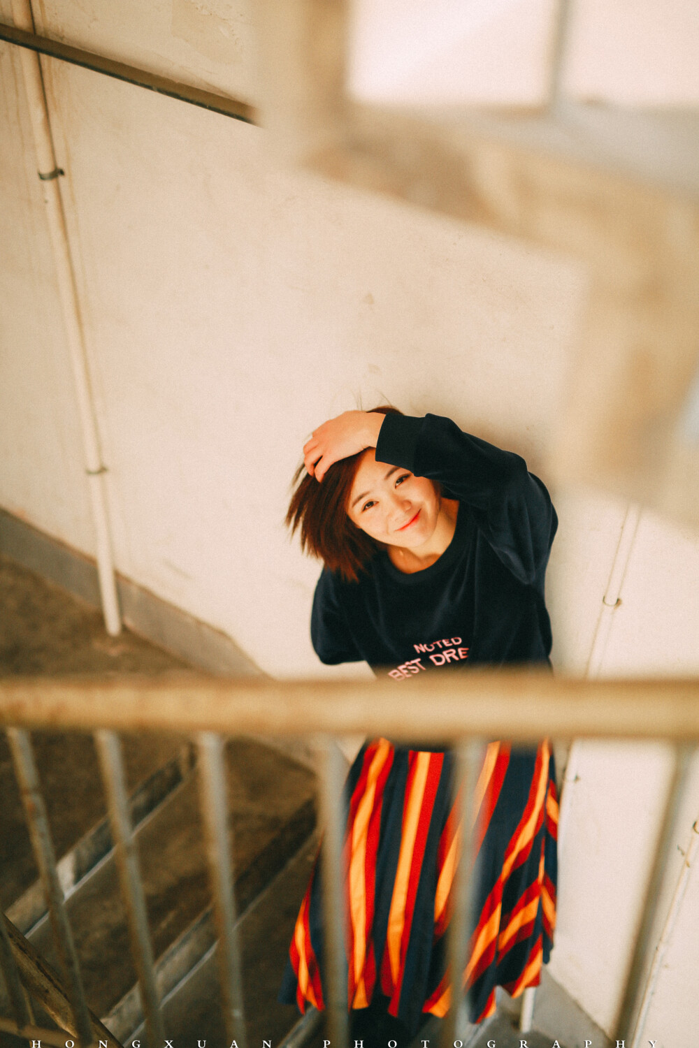 你是我的室友
摄影：洪小漩
出镜：羽希
过年在家，这是一个落寞的春节。我推掉了一些朋友的邀约，在家看日剧，或者陪妈妈寻山访寺，上香祈福。
今年回家发现全面禁烟花爆竹。我看看面目全非却被被赞颂的村庄，心下波澜不惊。这不是我长大的地方，而除夕夜少了鞭炮的轰鸣，也无非是让我更加坚信这一点。
初一那天， 恰好是羽希阳历生日，我给她发了个红包，稍稍聊了几句，新年问候。
年前最后一周的周末，我在社区楼道给她拍的照，因为不知道要写点什么文字，这才修完了却一直没腾出手来发布。
这个姑娘和我做室友也有两年了，我们一起经历了两轮涨房租，一起养了一只叫可乖的猫，一起换了热水器洗衣机，一起粉刷了墙壁。我为护她被一个男人指着鼻子破口大骂，胳膊上让人掐出淤青三周不褪，她为我冲上去直接和人扭打，架势就像一只疯狂的小牛。
我们一起过了一段互相搀扶的日子，那些时日，两个人走路都要左顾右盼，周遭弥漫着不安。
记得有一天，她搂着我泣不成声，哭着说抱歉。不擅长安慰人的我，僵硬地拍着她的后背，说没关系，说我一直在。
后来，从一场糟糕的感情泥沼中得以脱身的好姑娘，遇到了另一个心仪的男生。这个男生在工作日早上为她盛粥煎鸡蛋，周末陪