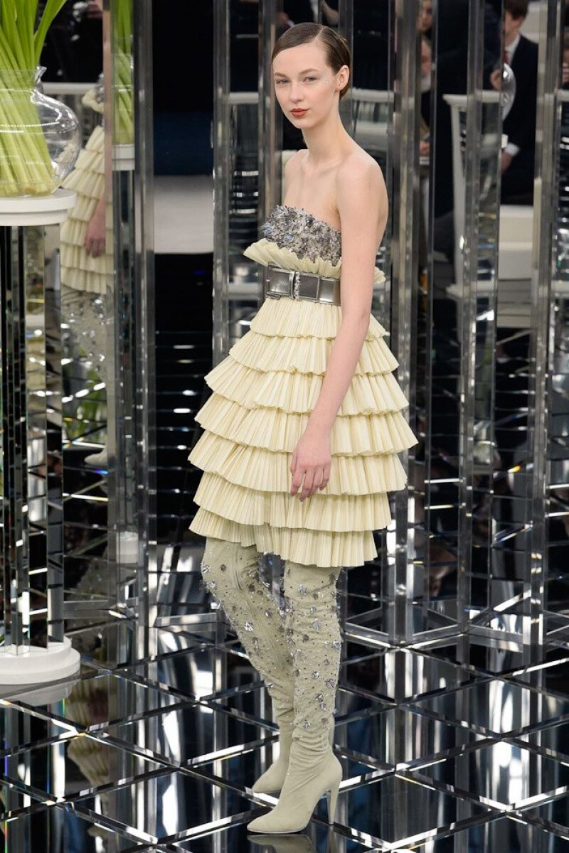 Chanel 2017 春夏高级定制 在卡尔•拉格斐的构想下，现场布置运用1930年代灵感和装饰艺术风格，打造出一个纯净华丽的镜面空间，令人想起通往香奈儿高级定制服沙龙的著名镜梯。秀场四周设有多排舒适的米色沙发，中央竖起宛如万花筒般的镜面圆柱，模特们依次从柱前走过，一袭袭优雅身姿在镜面棱柱和烟色镜砖菱格纹地面中交映折射，流转无尽衣香鬓影～