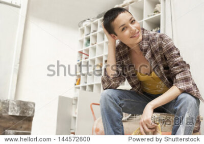 Portrait of young female painter on work break in tool room