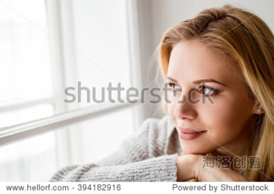 Woman sitting on window sill, looking out of window