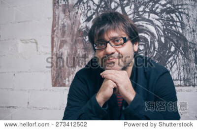 Closeup of painter artist posing in front of one modern artwork in his studio