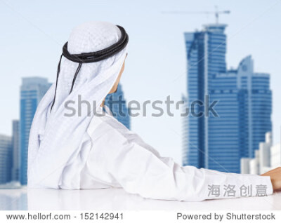 Successful Arab businessman looking out the window of his office.