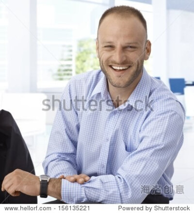 Happy mid-adult businessman sitting at office, laughing.