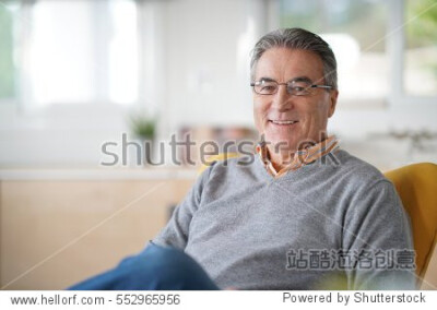 Smiling senior man with eyeglasses relaxing in armchair