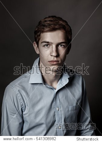 Portrait of serious, sad, thoughtful handsome young man on gray background, teenager in studio, close up